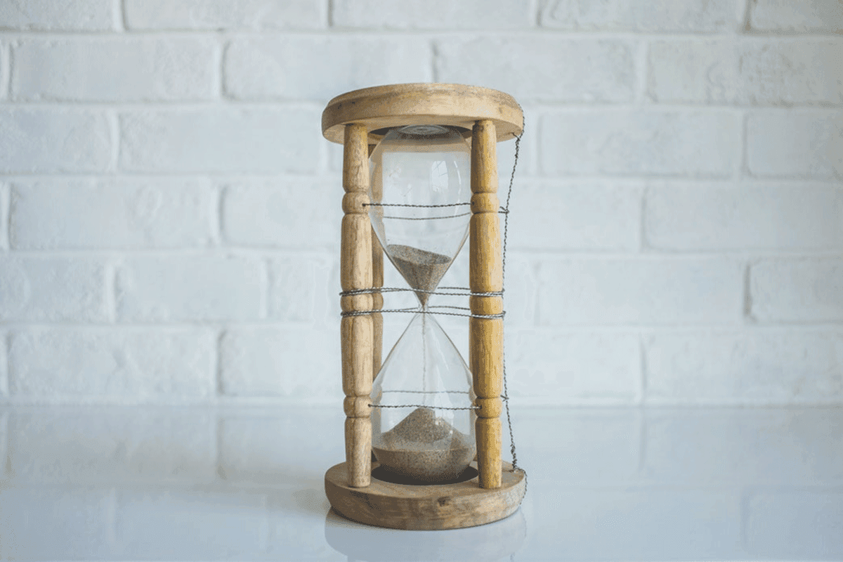 An hourglass filled with sand resting on a white table, symbolizing the passage of time and the fleeting nature of moments.