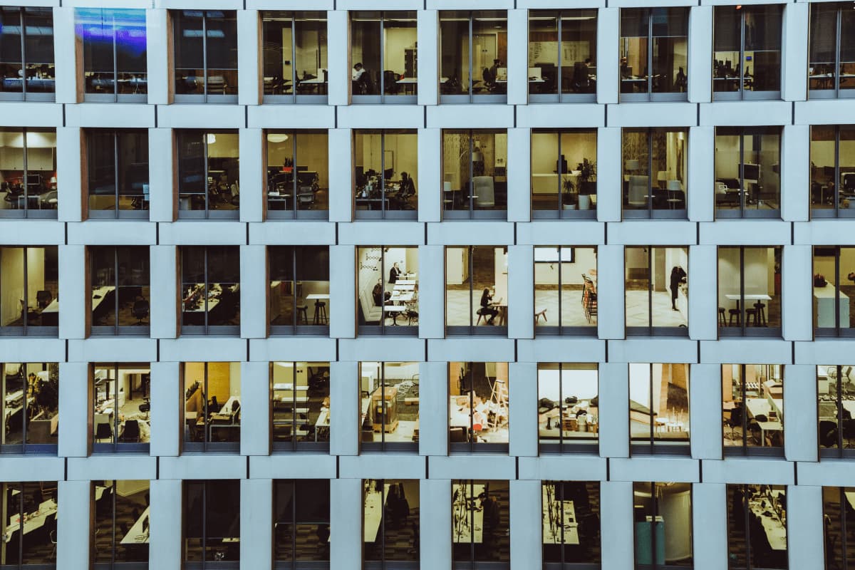 An image of a bustling office building with numerous windows and a crowd of people going about their daily activities.