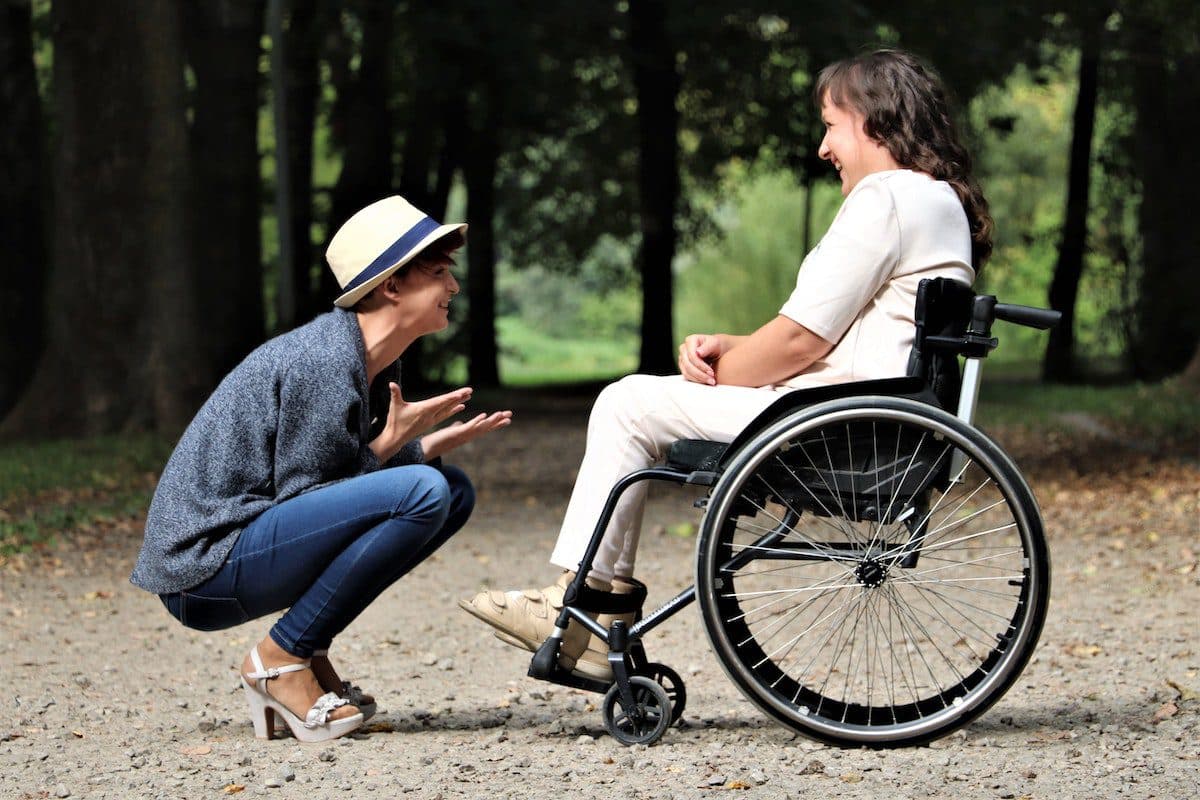 A woman in a wheelchair respectfully converses with another woman, displaying empathy and understanding.