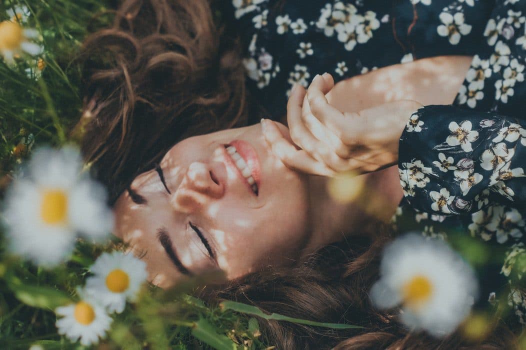 The girl relaxes and smiles in the garden of flowers