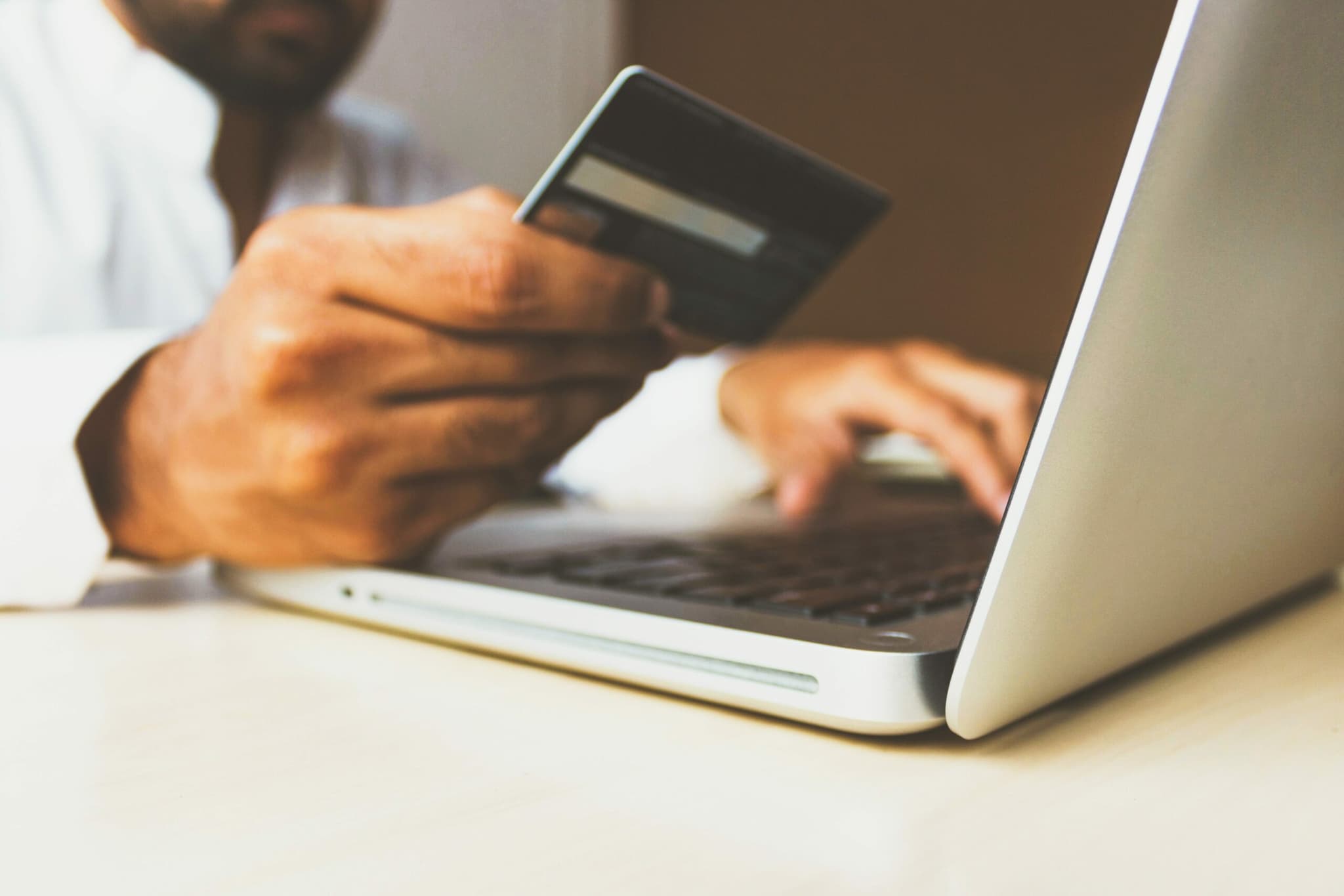 a person holding a credit card and typing on a laptop