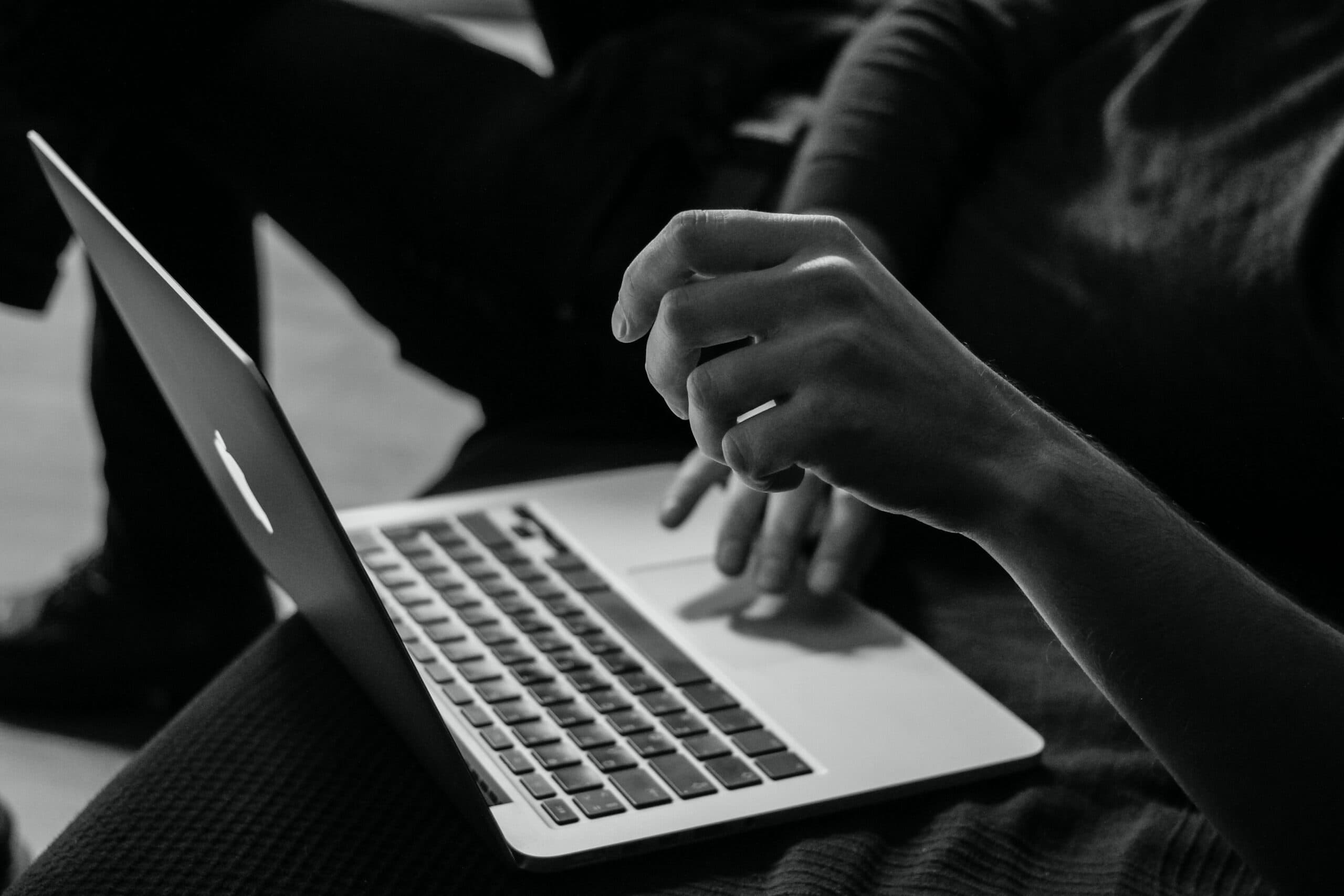 A person engrossed in work on a couch, using a laptop.