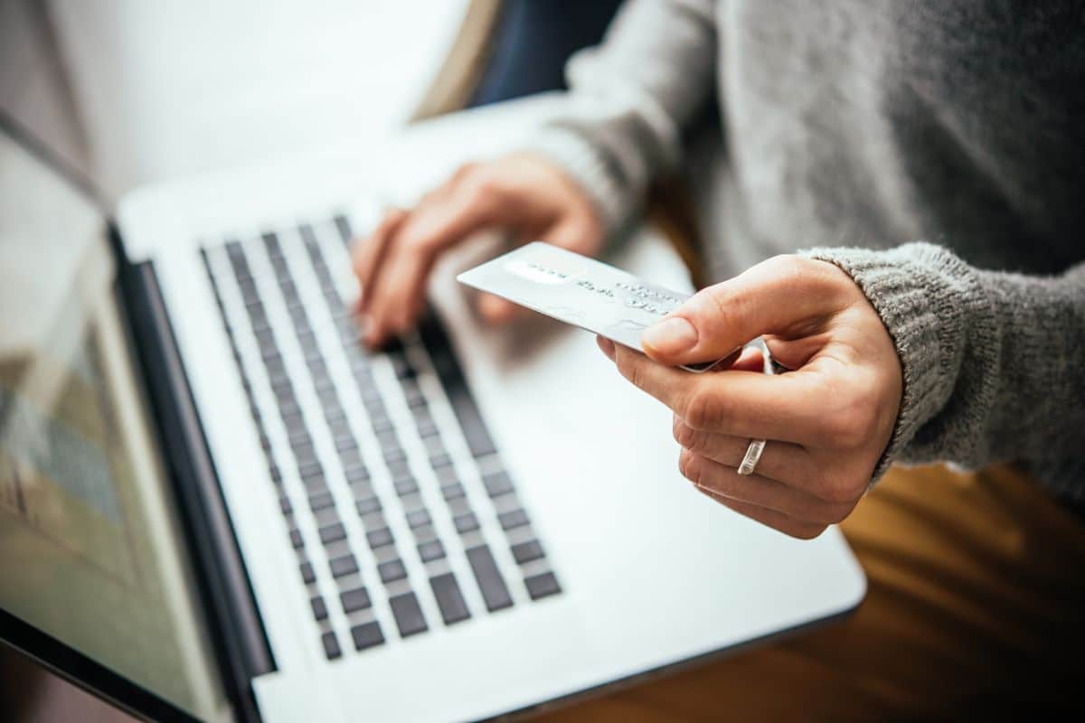 a person holding a credit card and typing on a laptop