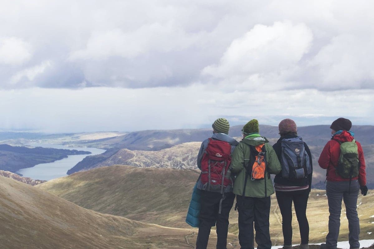 a group of people standing on a mountain looking at a body of water