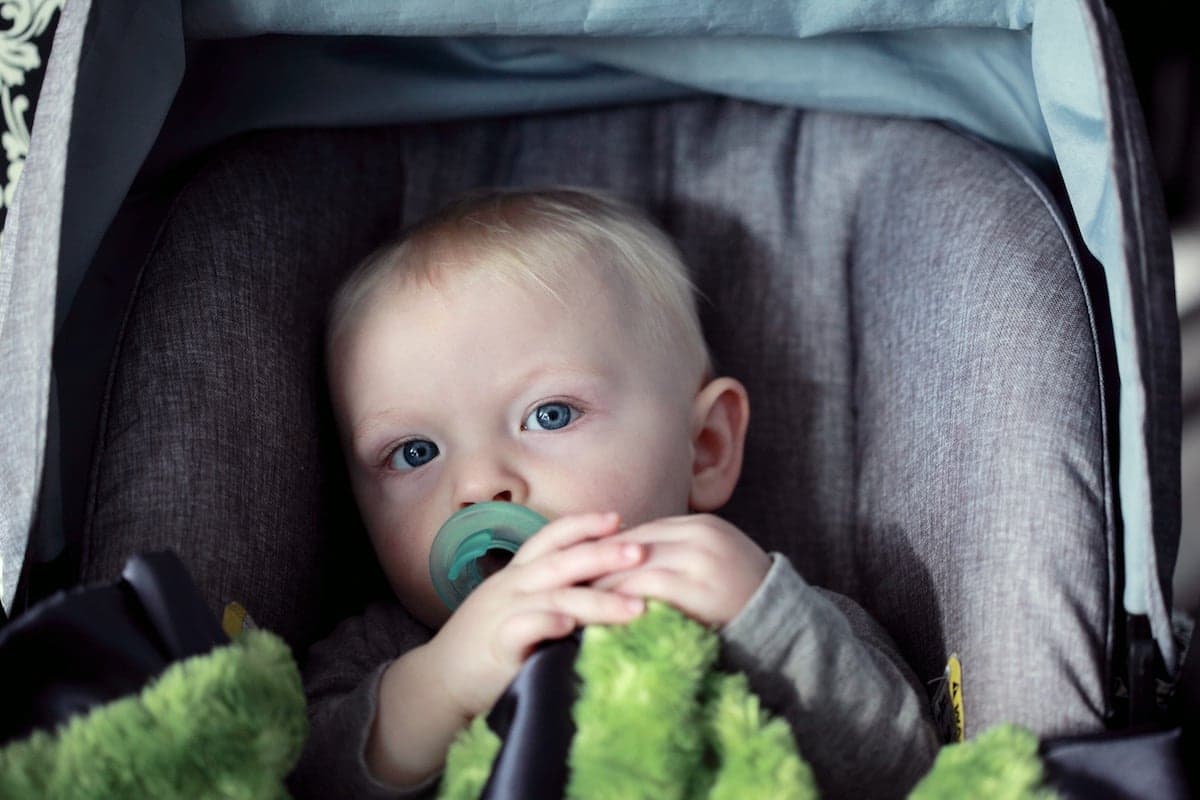 a baby with a pacifier in a car seat