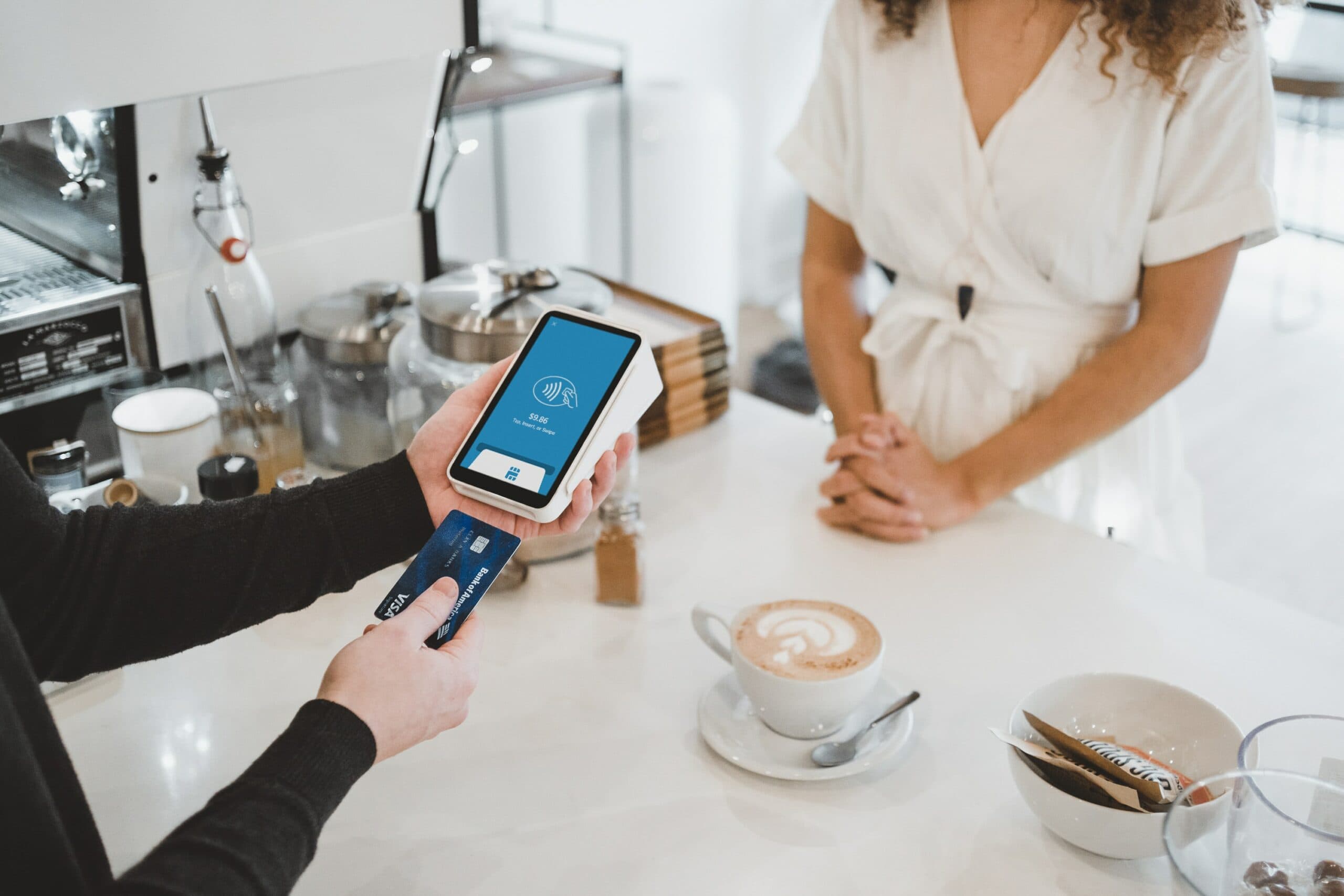 a person holding a device and a credit card to payment