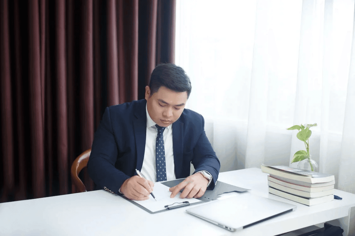 a person sitting at a desk writing on a clipboard