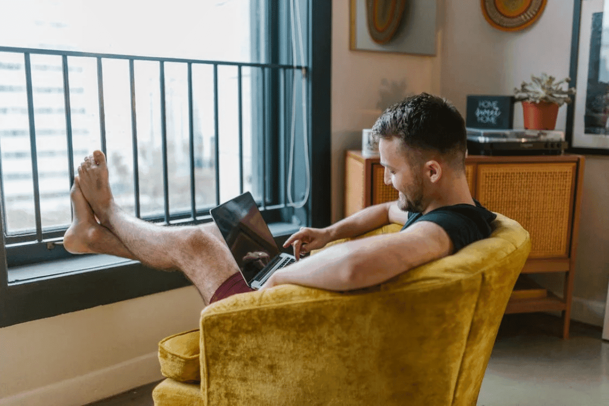 A person sitting comfortably with their feet on a laptop.