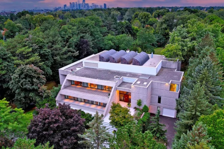 An aerial view of a contemporary residence nestled amidst a lush canopy of trees.