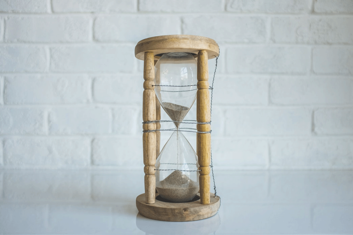An hourglass filled with sand resting on a white table, symbolizing the passage of time and the fleeting nature of moments.