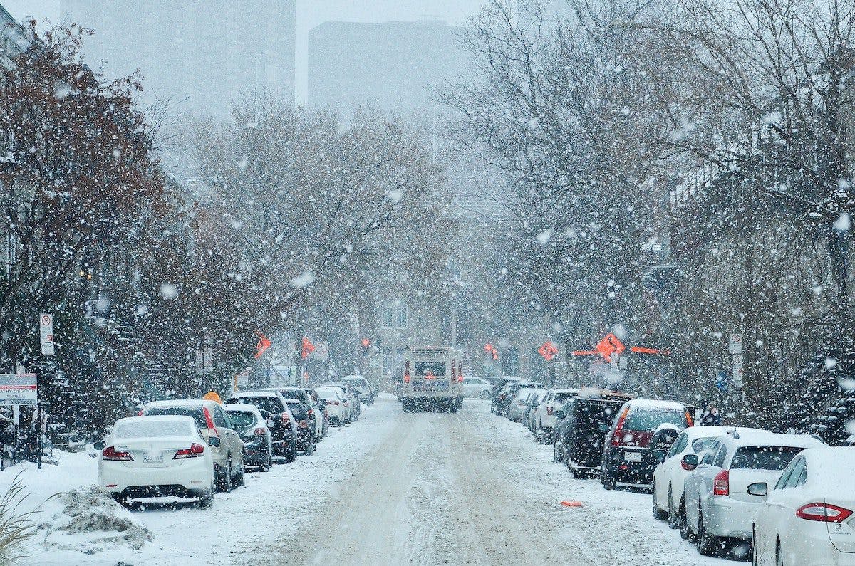 a snow covered street with cars and trees