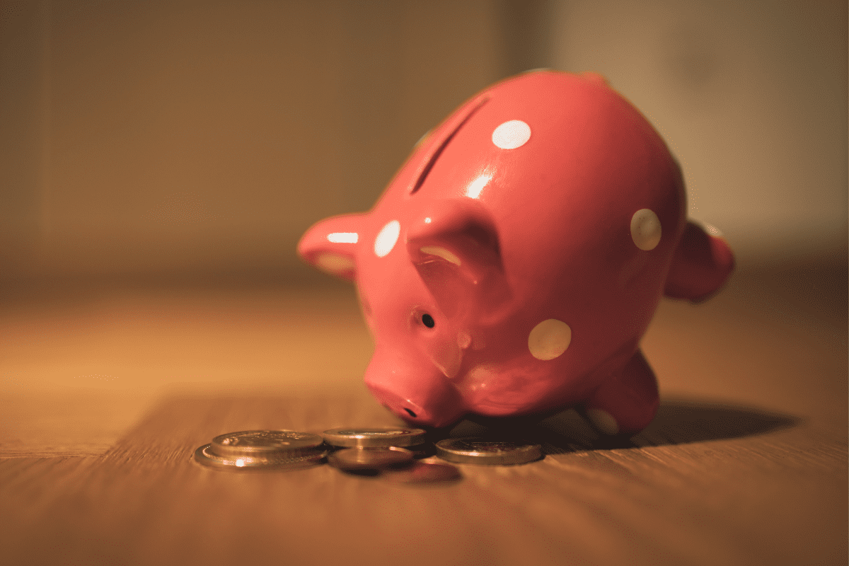 A piggy bank filled with coins sits on a wooden table, symbolizing savings and financial security.