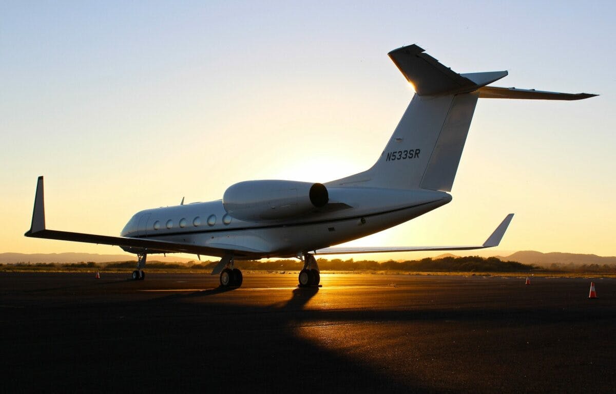 A private jet parked on the tarmac at sunset, exuding elegance and luxury, ready to embark on its next glamorous journey.
