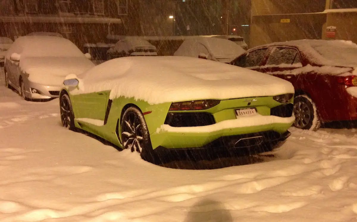 A green sports car parked in the snow, showcasing its sleek design amidst the wintry landscape.