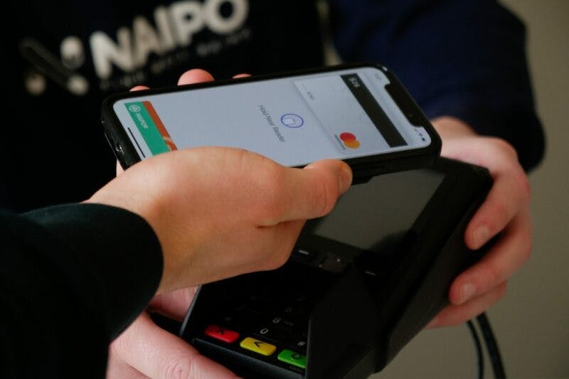 a person holding a phone and a credit card reader