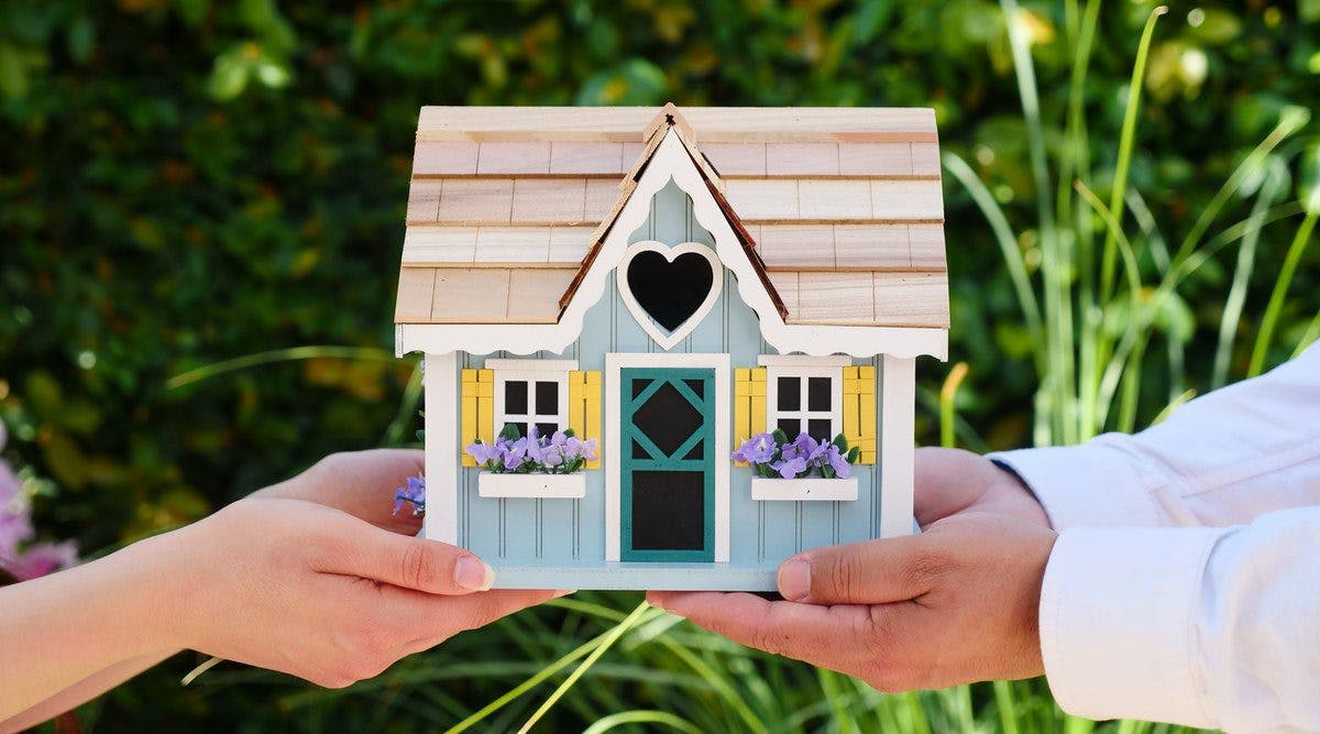 two person holding a small house