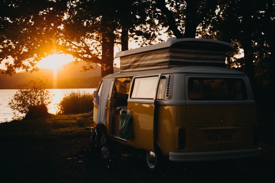 VW camper van parked near lake during sunset