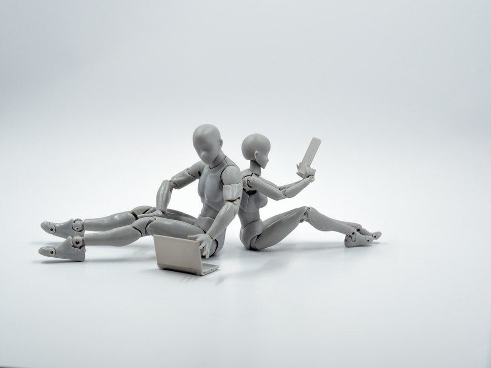 Two robots sitting on a white surface, showcasing miniature figures in a serene setting.