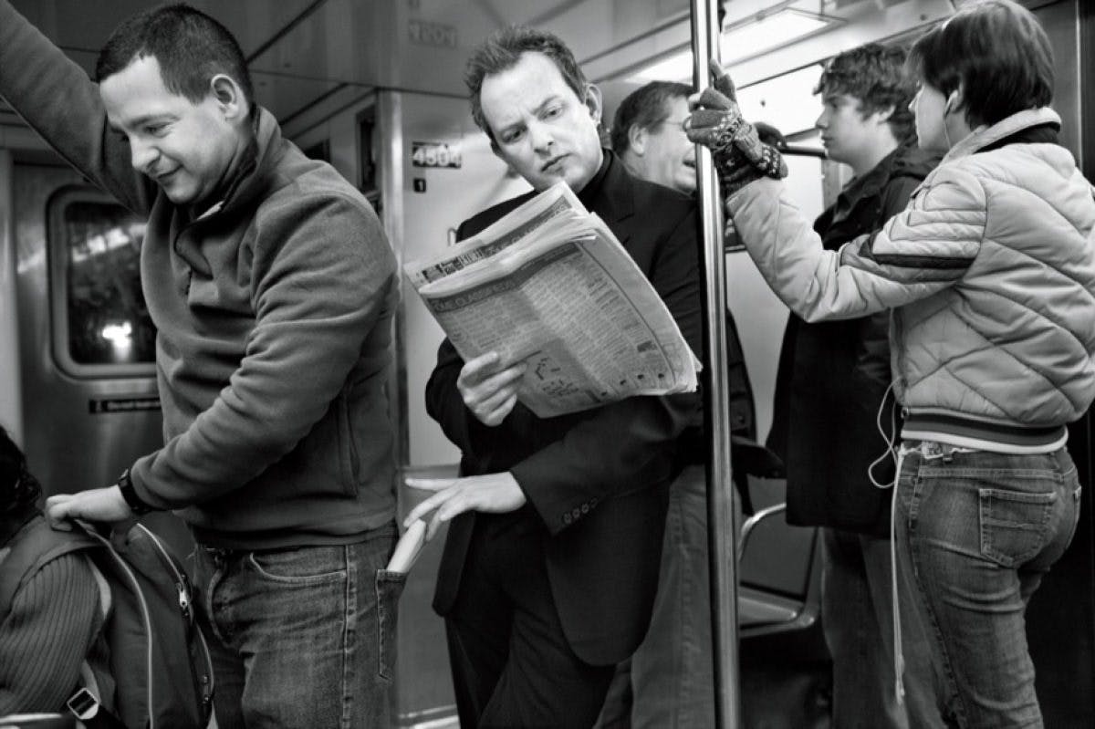 An artistic black and white photograph depicting individuals traveling on a subway, illustrating the dynamic nature of city life.