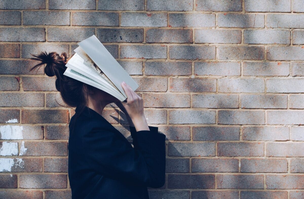 A woman engrossed in reading, holding a book close to her face, captivated by the words on the pages.