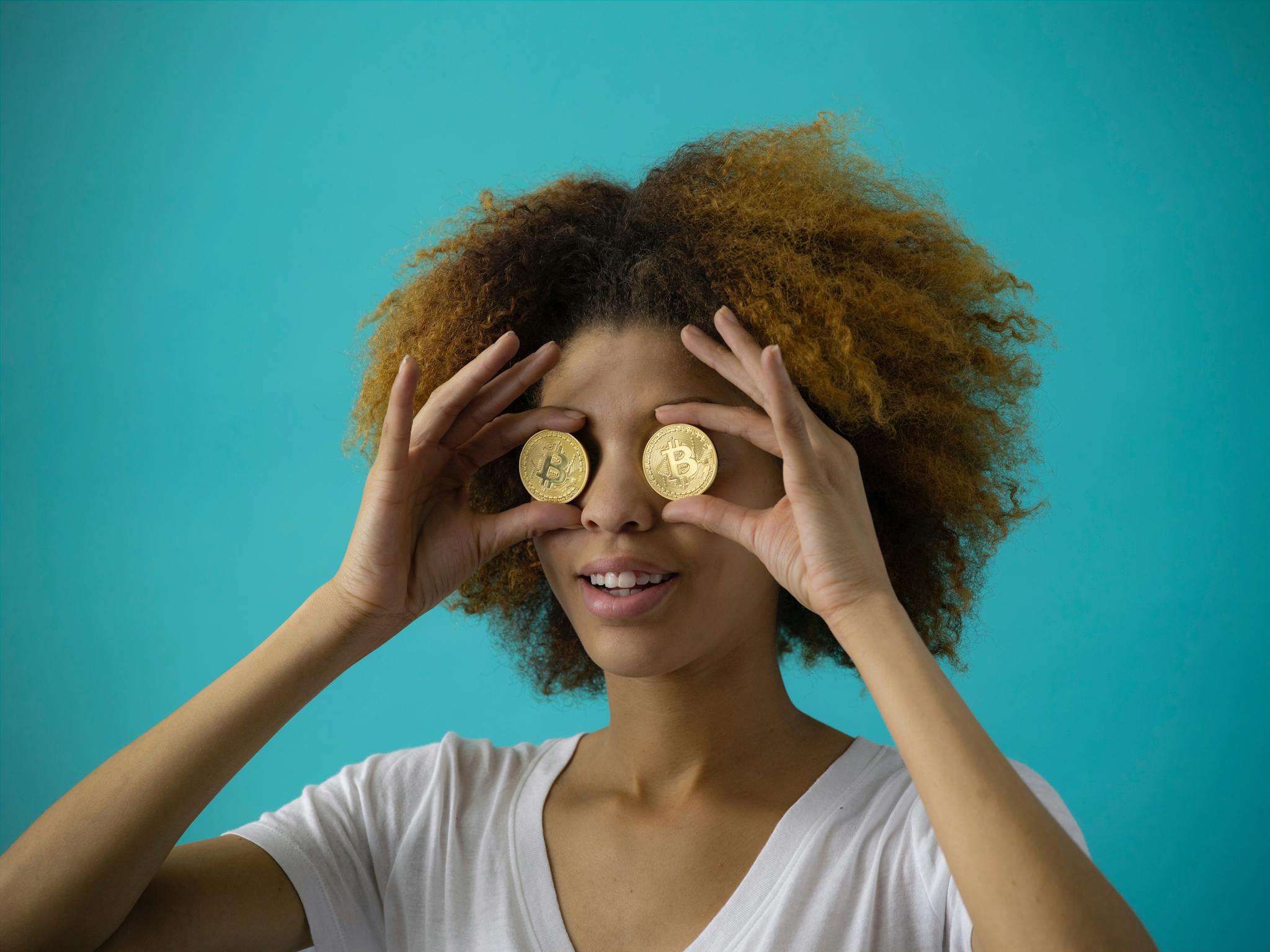 a woman holding two gold coins over her eyes