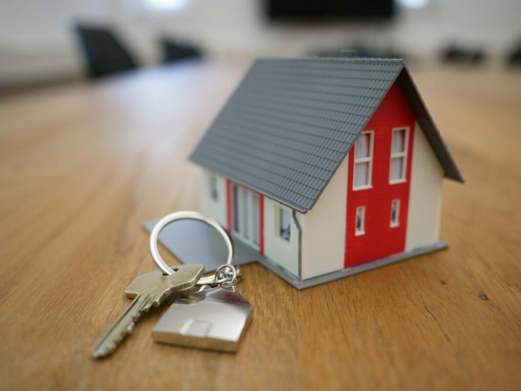 Une maison à coté d'un porte-clé qui représente l'acquisition d'une maison