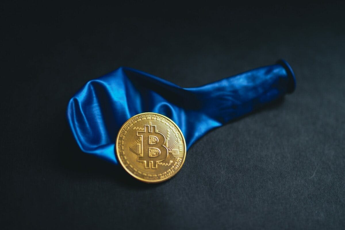a gold bitcoin with a blue balloon