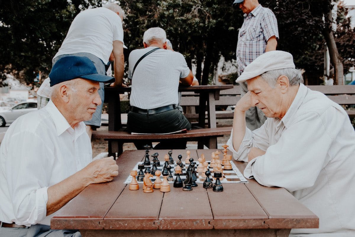 two men playing chess at a picnic table