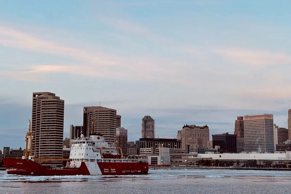 A red boat glides through the water, surrounded by the city's skyline.