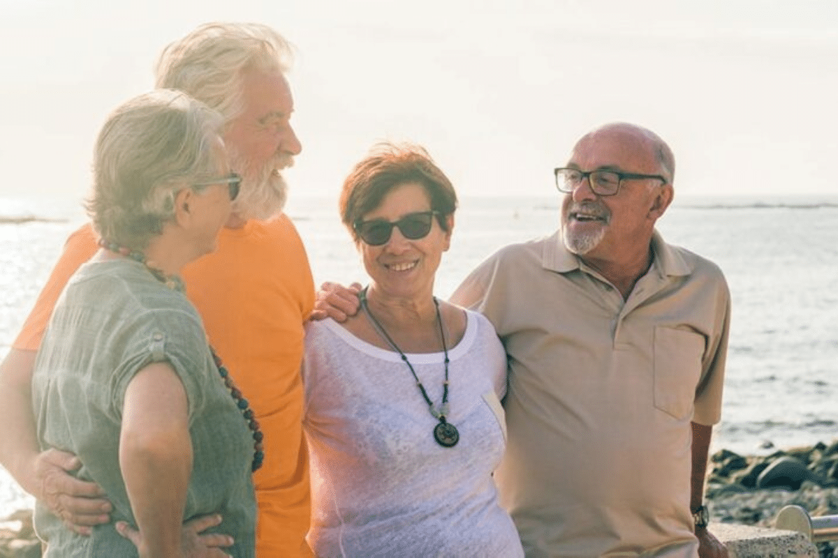 a group of senior couples standing together on the beach