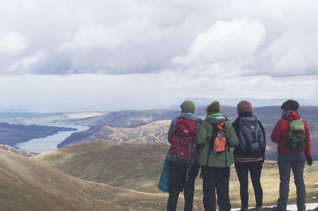 a group of people standing on a mountain looking at a body of water