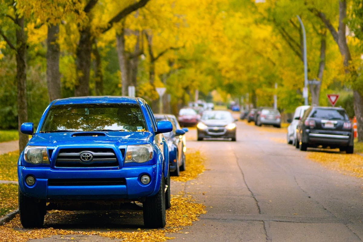 a blue truck parked on a street with cars parked on the side
