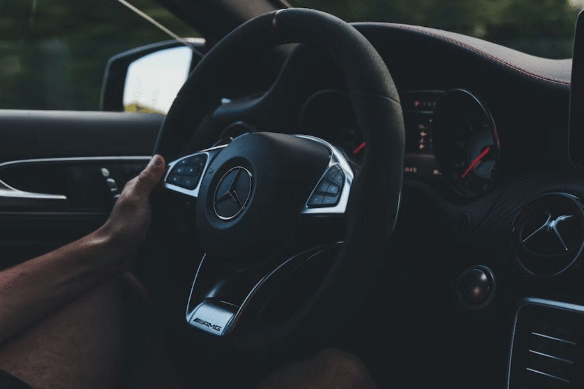 a hand on the steering wheel of a car