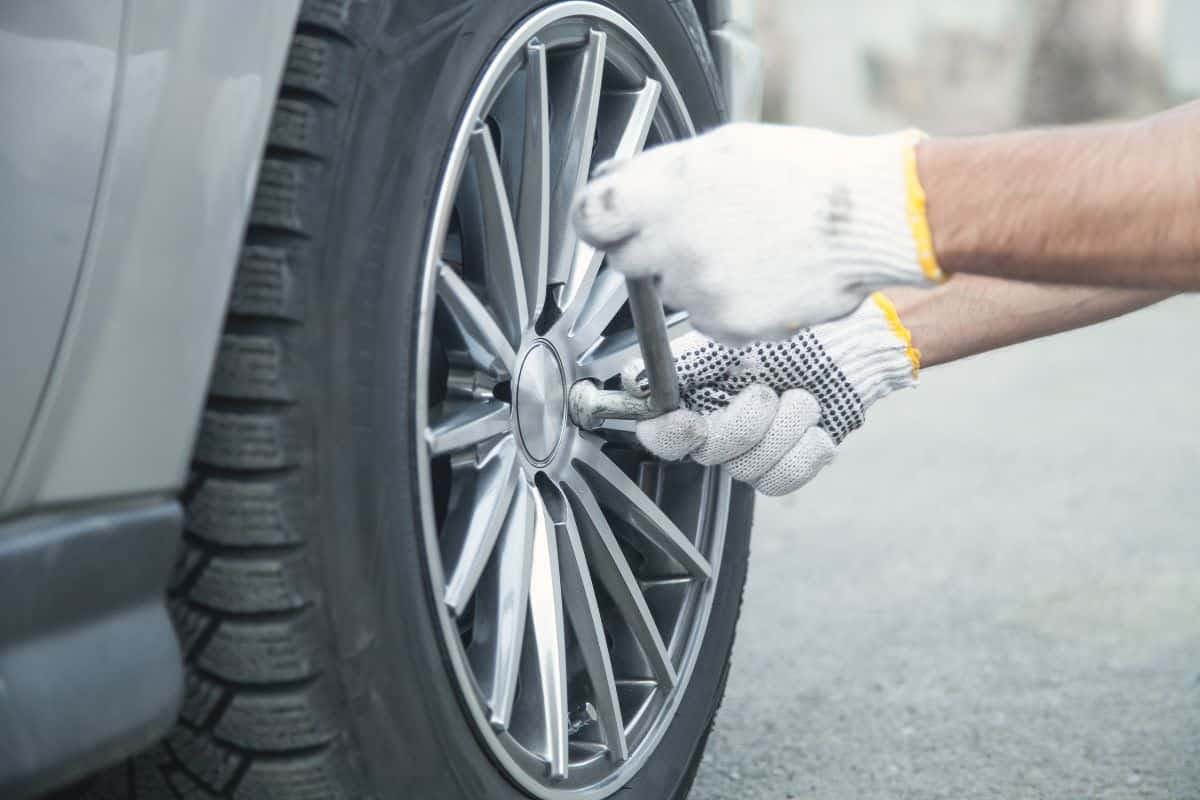 a person holding a wrench on a car tire