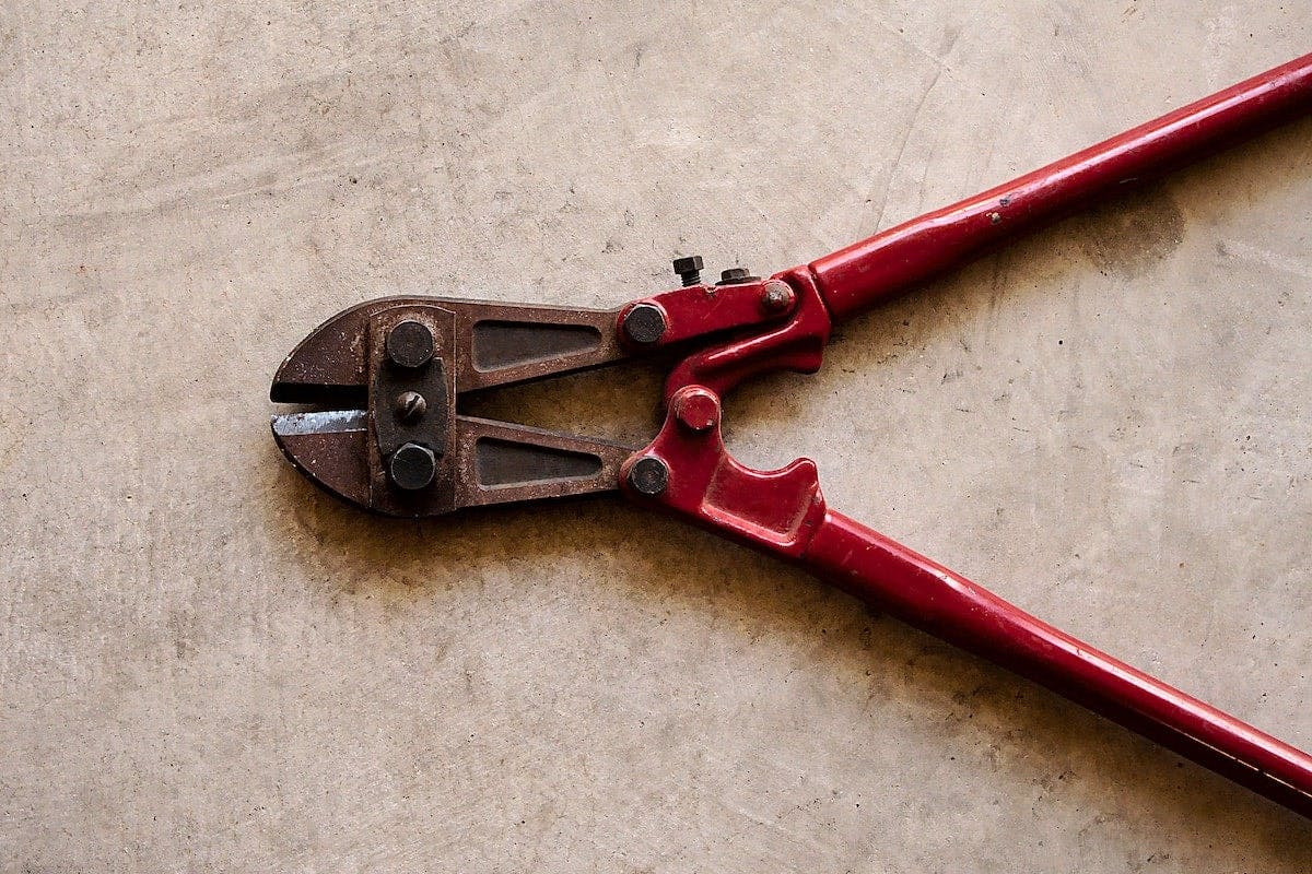 a red bolt cutter on a concrete surface