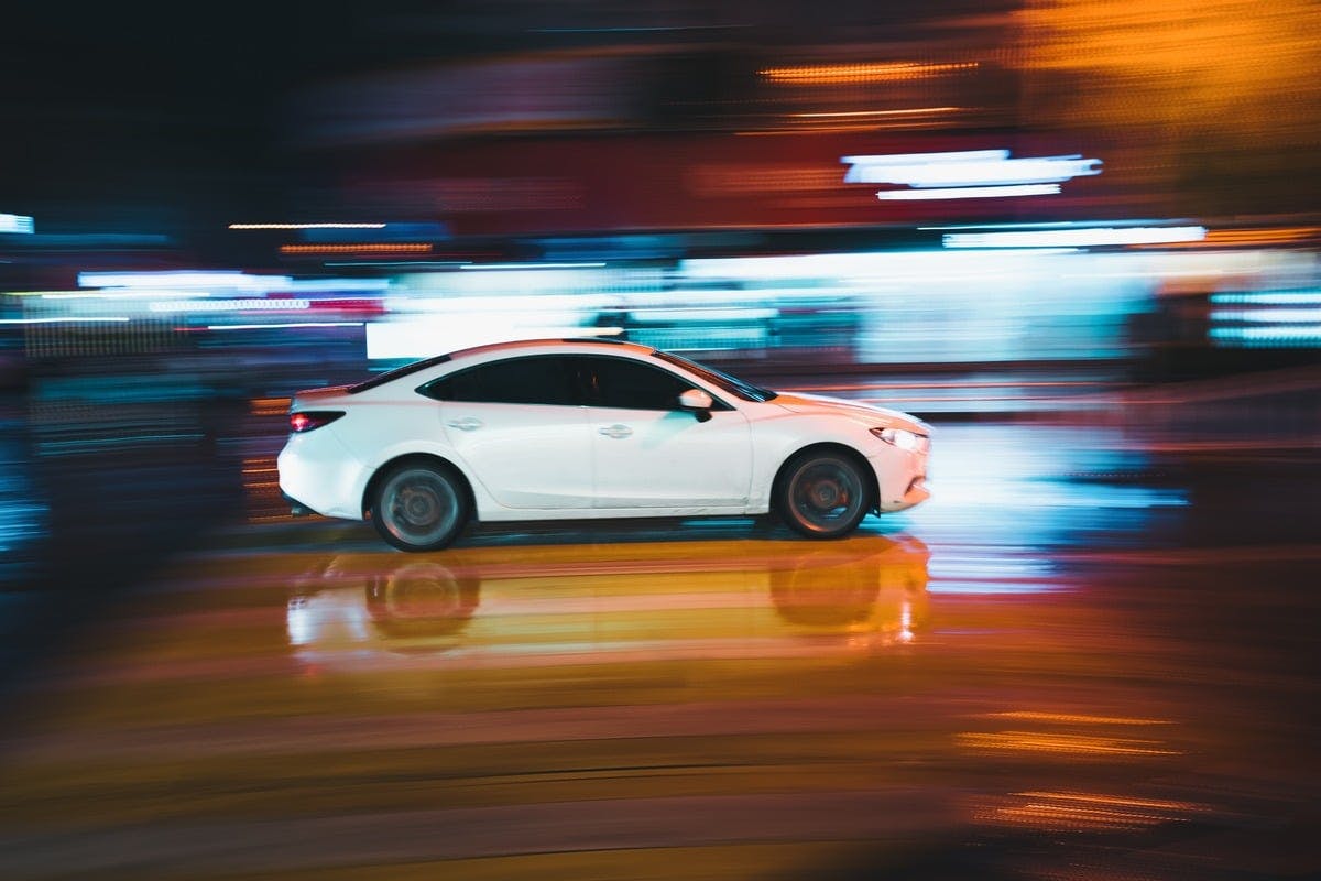 a white car on a wet road at night
