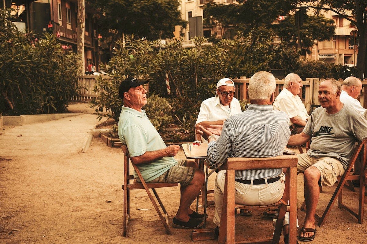 A group of senior men spending leisure time playing cards amidst nature's beauty.