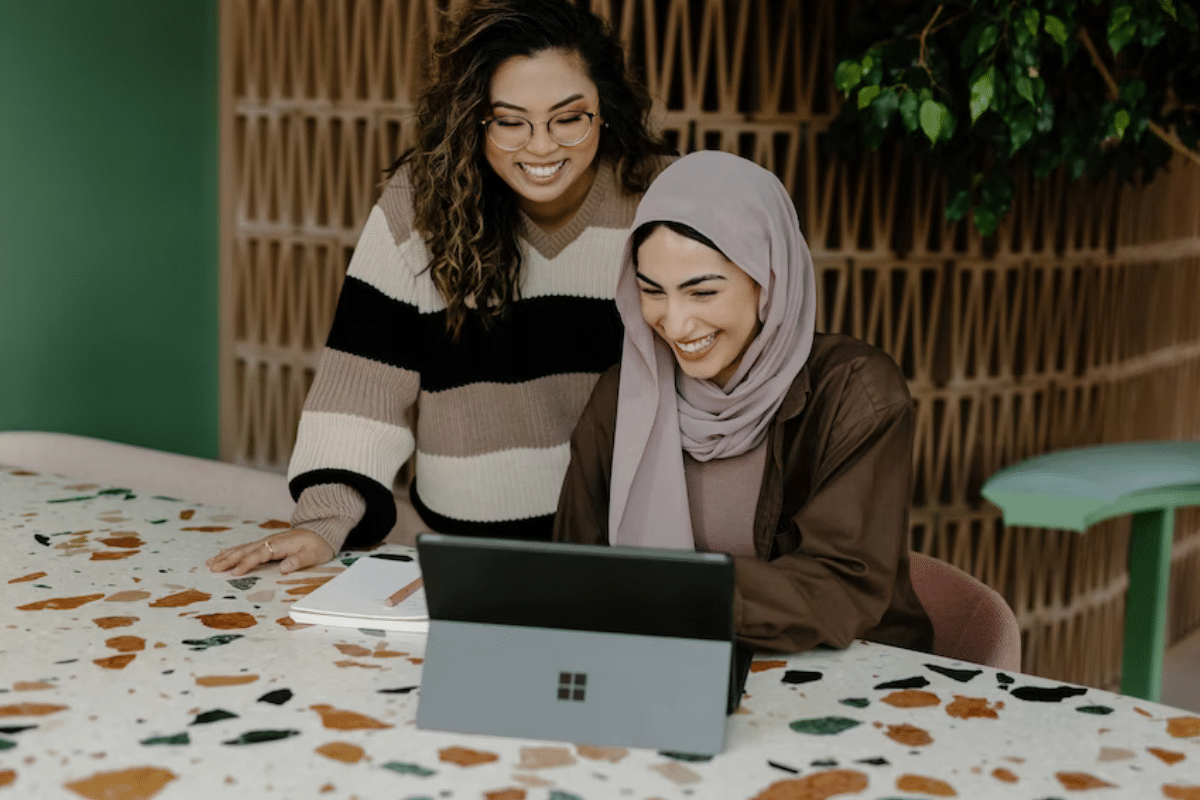 two women looking at a laptop and smiling