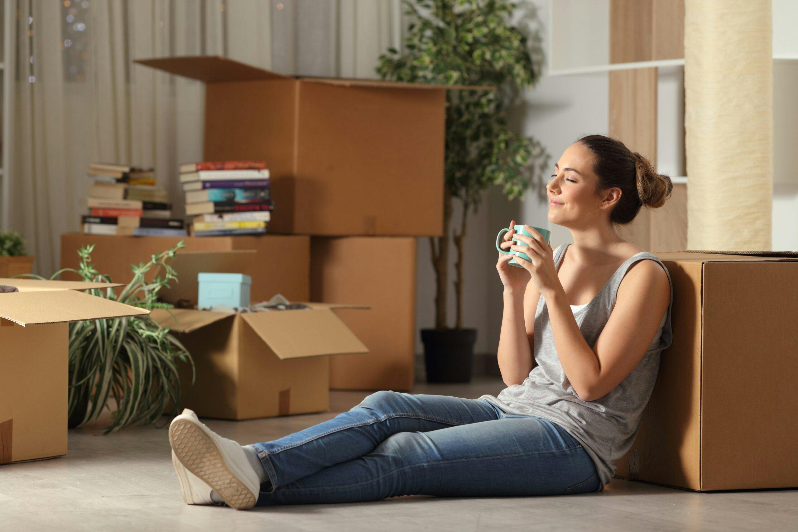 A woman surrounded by boxes, sitting on the floor, possibly during a move or organizing task.