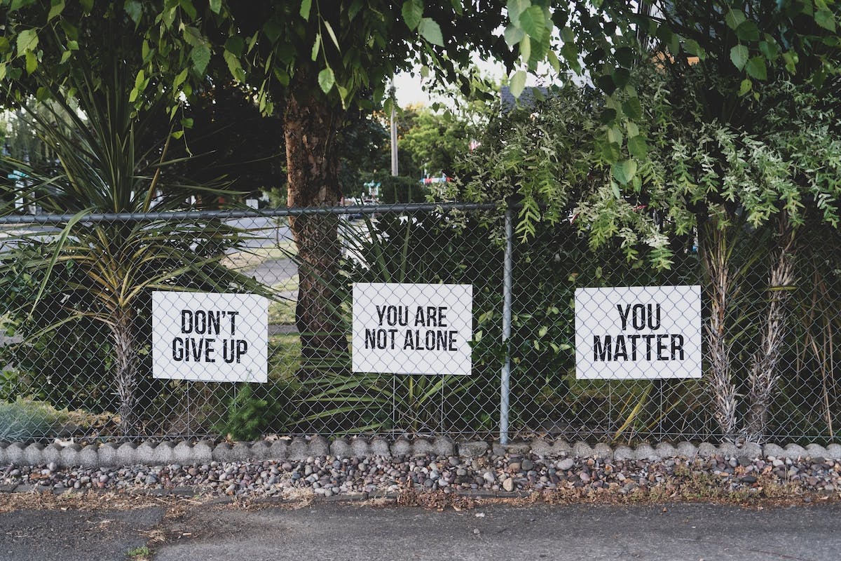 a fence with signs on it:: Don't give up, You are not alone, You matter