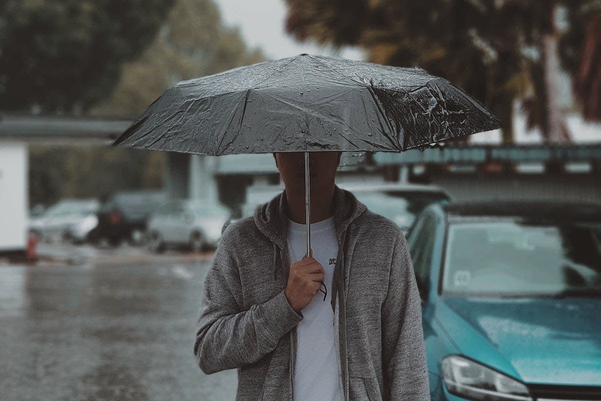 A person sheltering from rain under an umbrella.