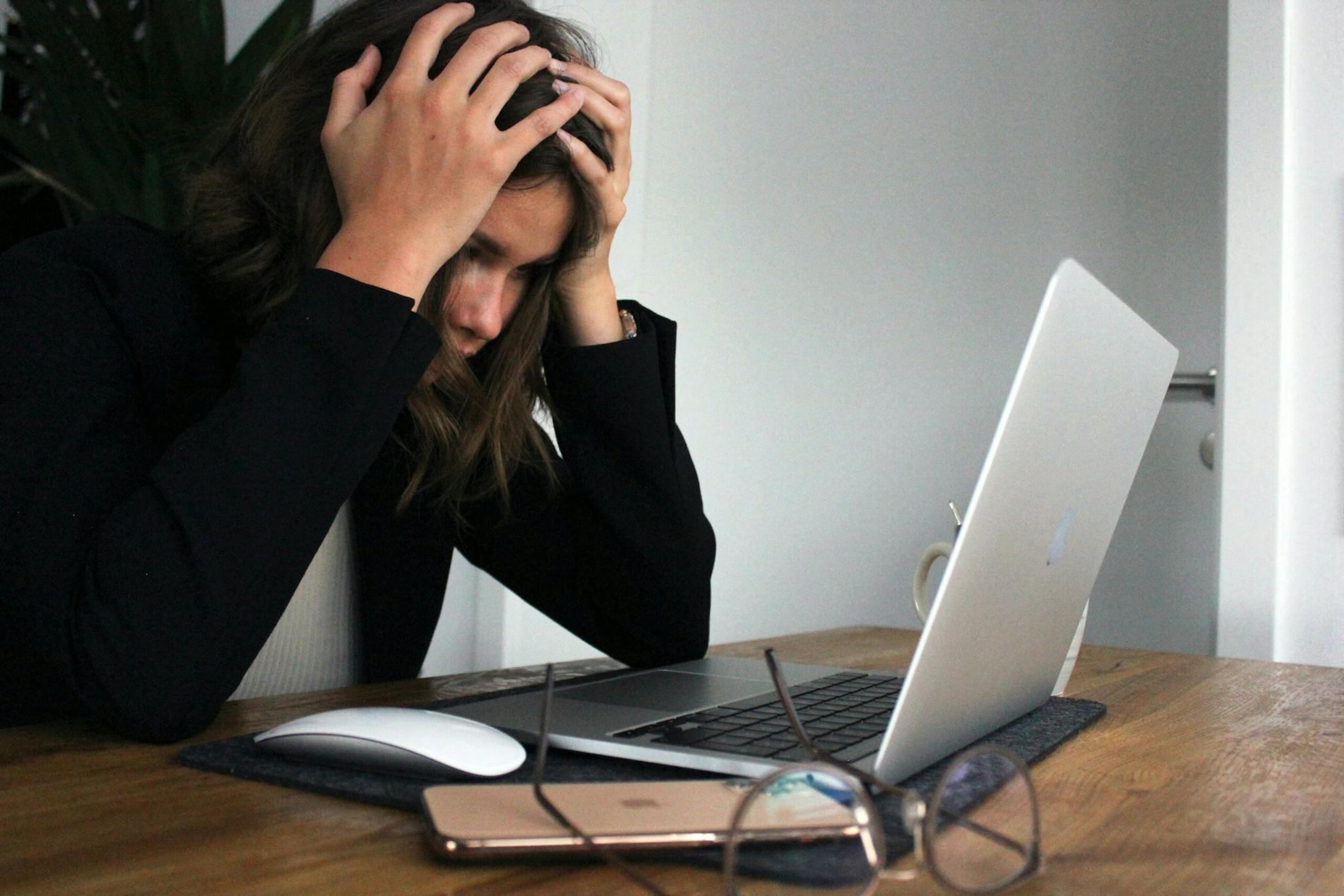 a girl holding her head in front of a laptop