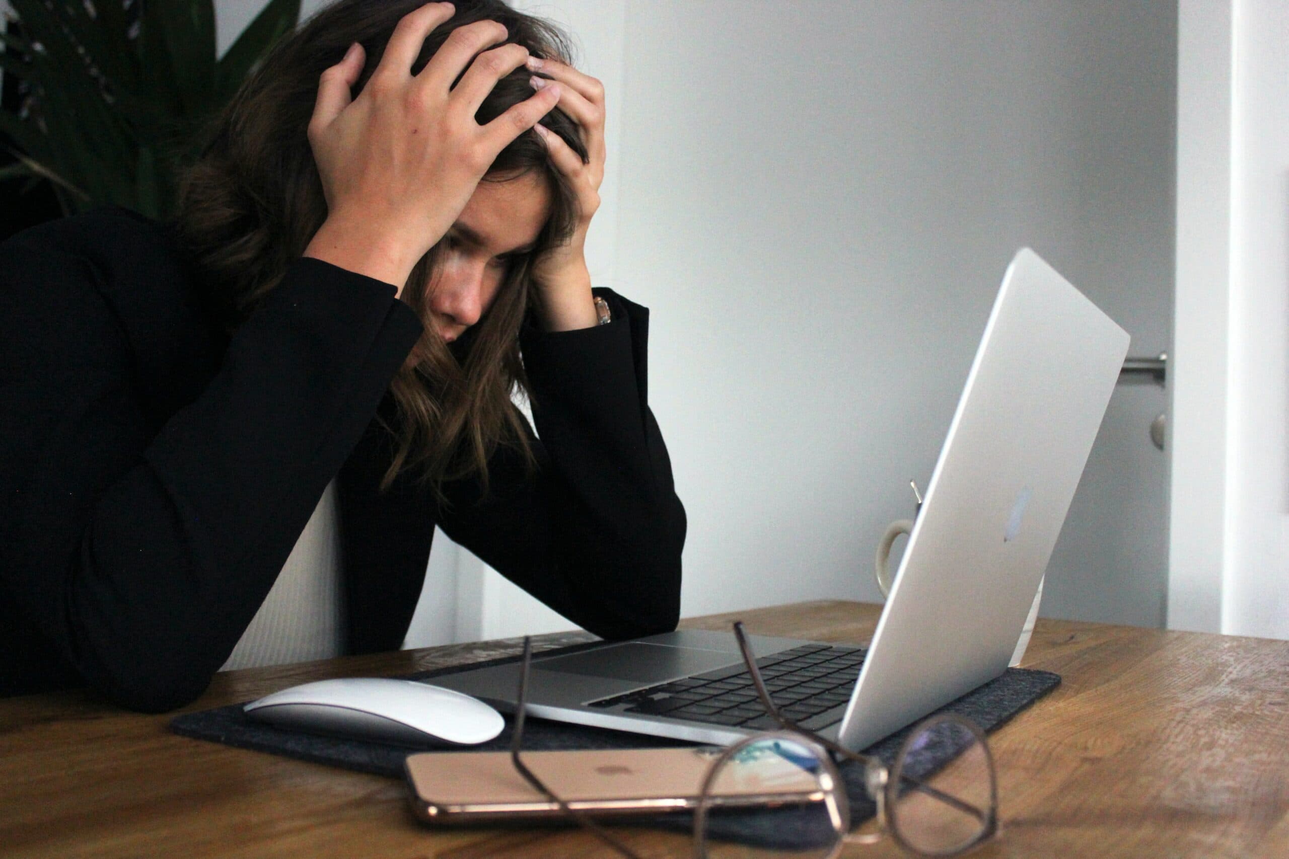 a girl holding her head in front of a laptop