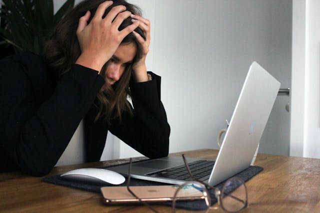 a girl holding her head in front of a laptop