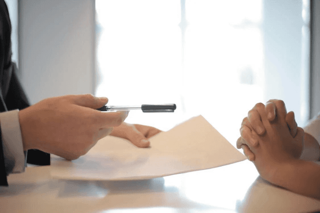 a person holding a pen over a paper