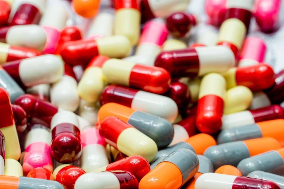 Many colorful pills scattered on a table, forming a vibrant mosaic of various shapes and sizes.