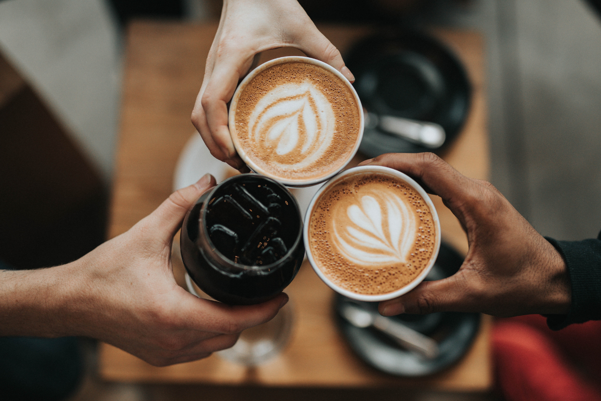 a group of hands holding cups of coffee