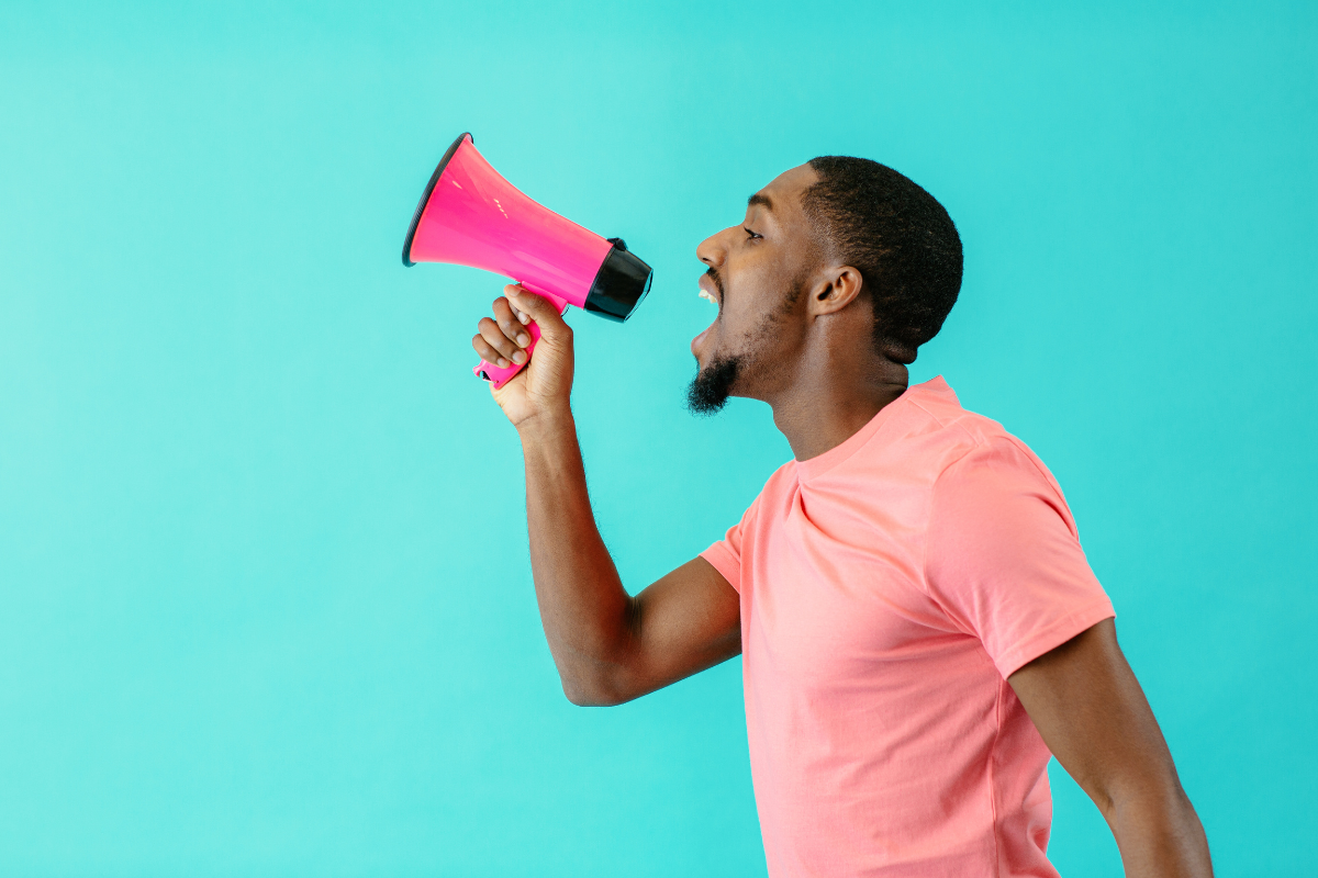 A man passionately vocalizing through a vibrant pink megaphone
