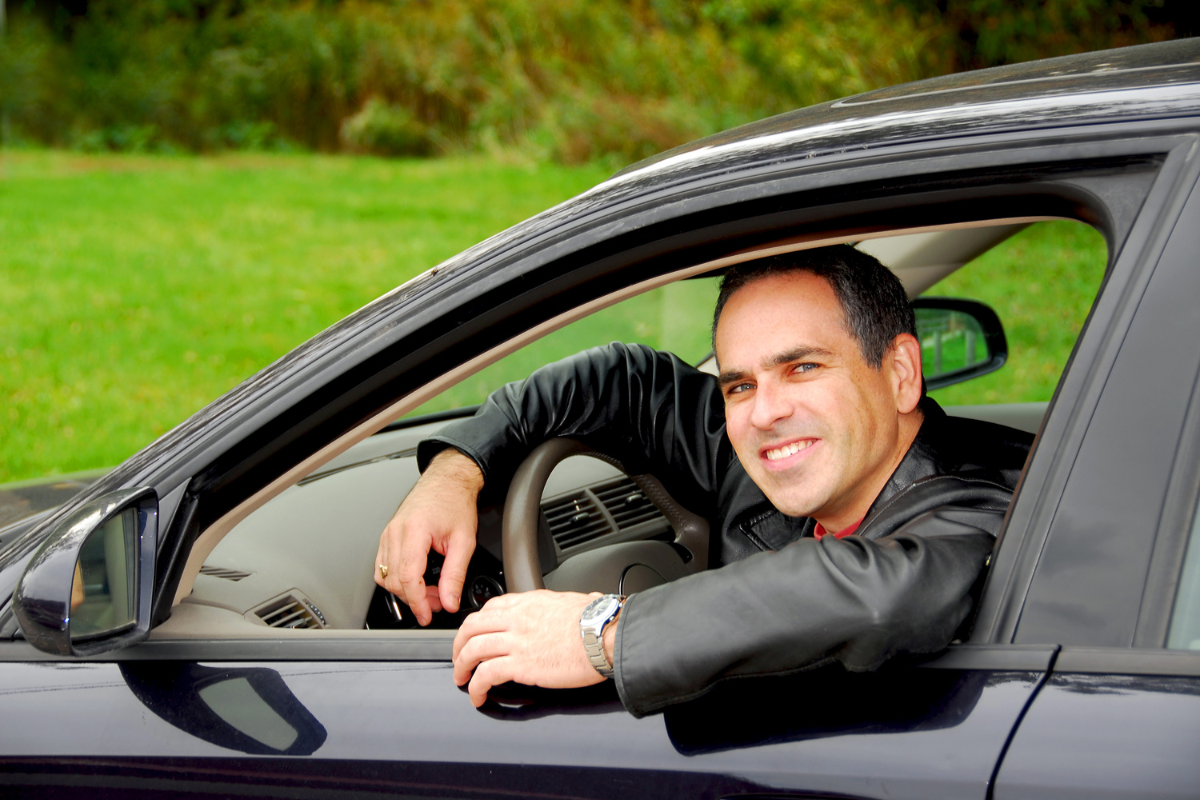 A man with a cheerful expression driving a car