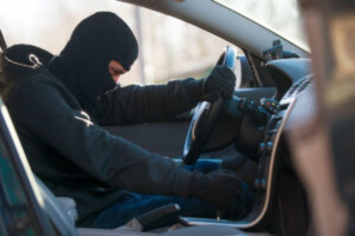 A person wearing a black mask and holding a steering wheel